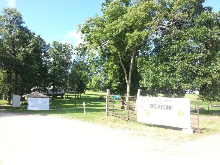 a sign is next to an outhouse in a park