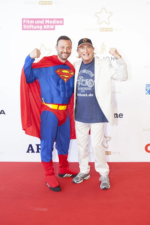 a man in superman suit posing with a man dressed up as a super hero