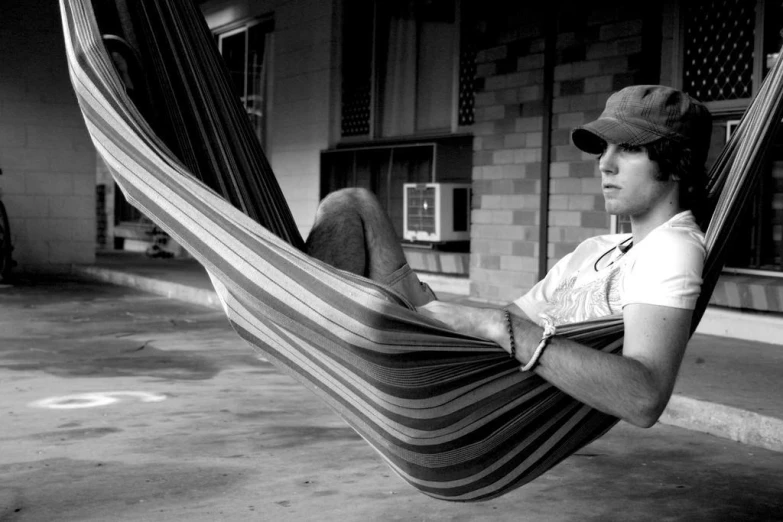 a man resting on his hammock outside a building