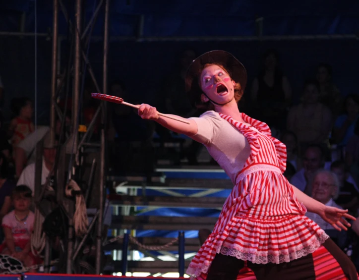 a woman on stage wearing a costume with a cane in the air