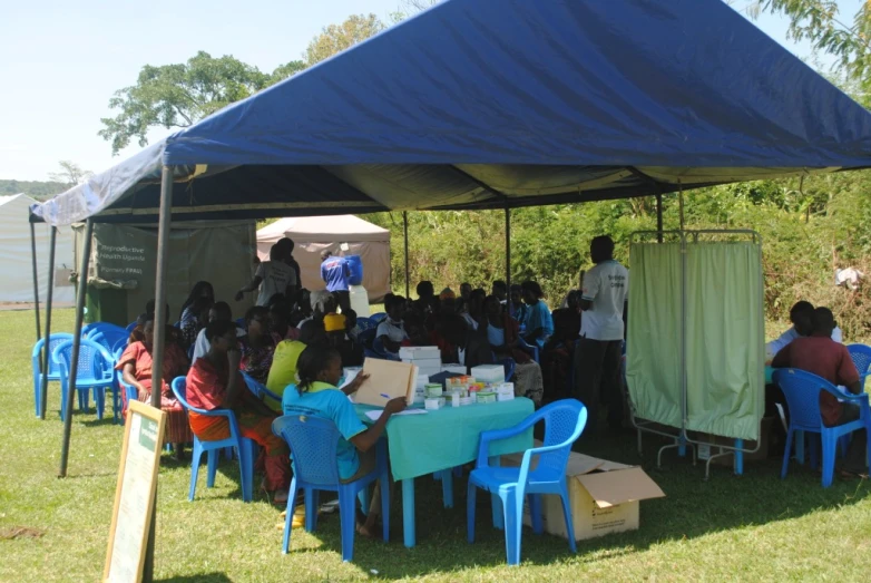 a group of people sitting around table and chairs in front of a tent