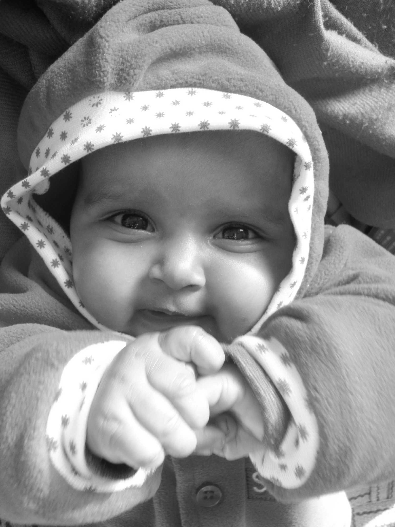 a baby in a robe smiles and sits on the ground