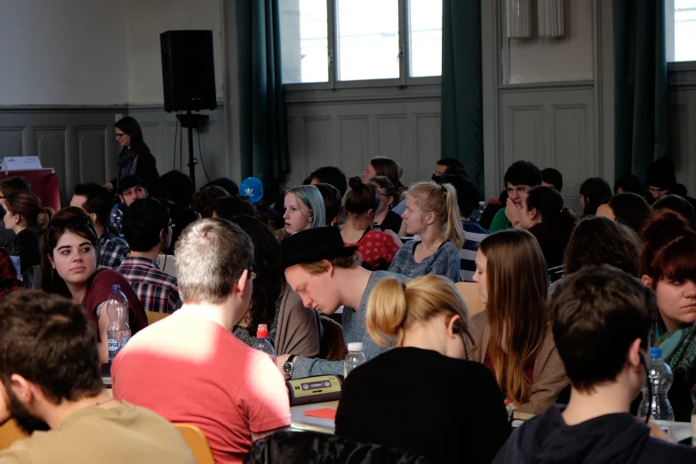 people in a room are sitting in chairs and one is speaking