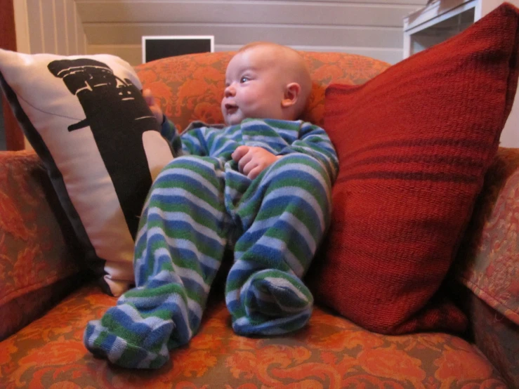 a baby sitting in a chair with pillows