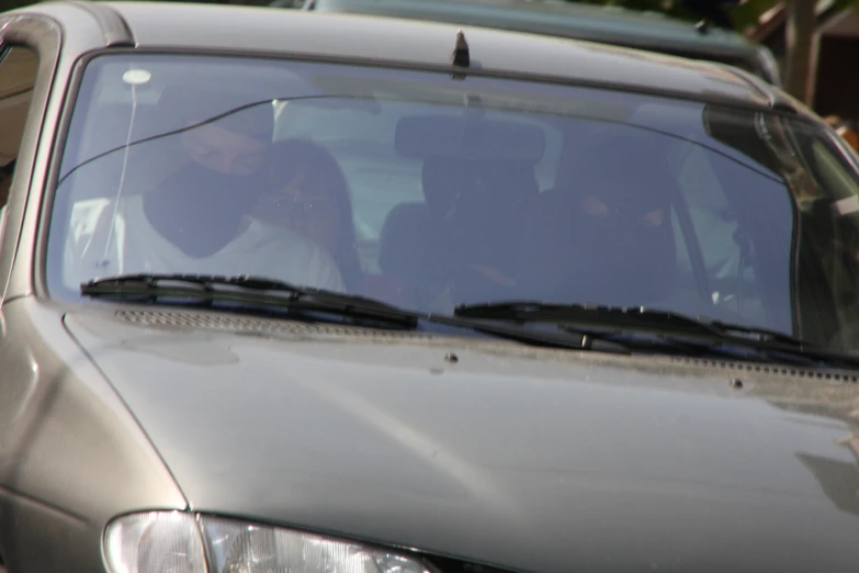 several people sit behind the wheel of a silver vehicle