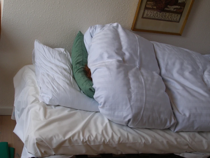 an unmade bed has two pillows and a pillow on top