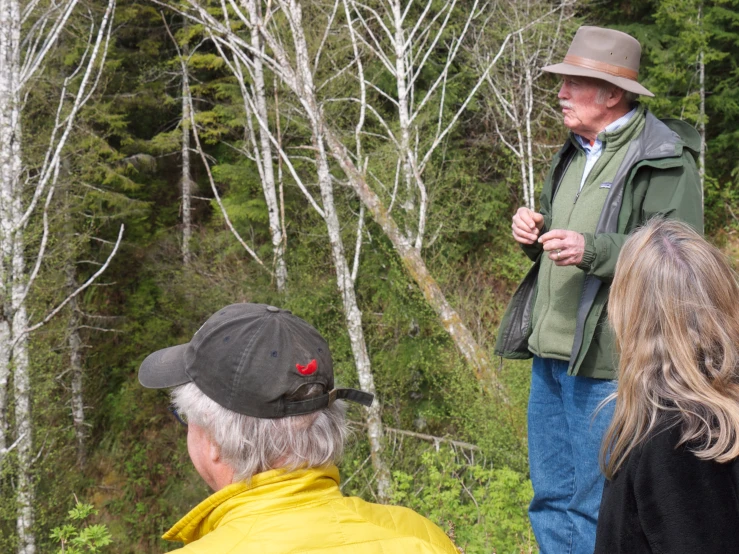 an elderly man is standing near a forest