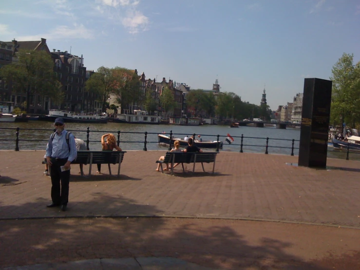 three men on benches near a river with a dog