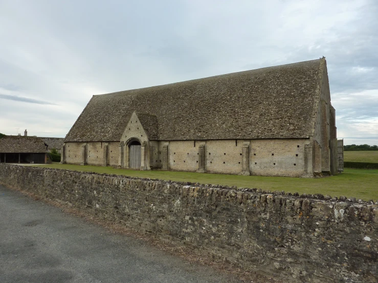 an old stone barn sitting on top of a lush green field