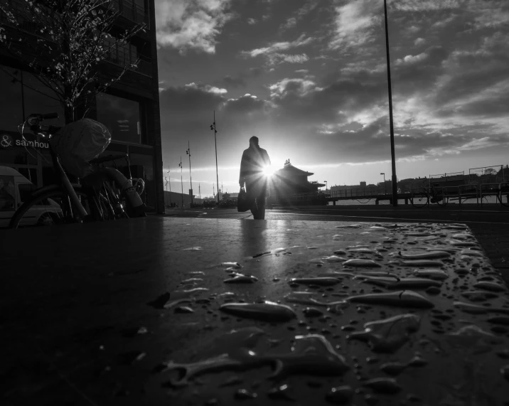 the person is walking across a pavement in the rain