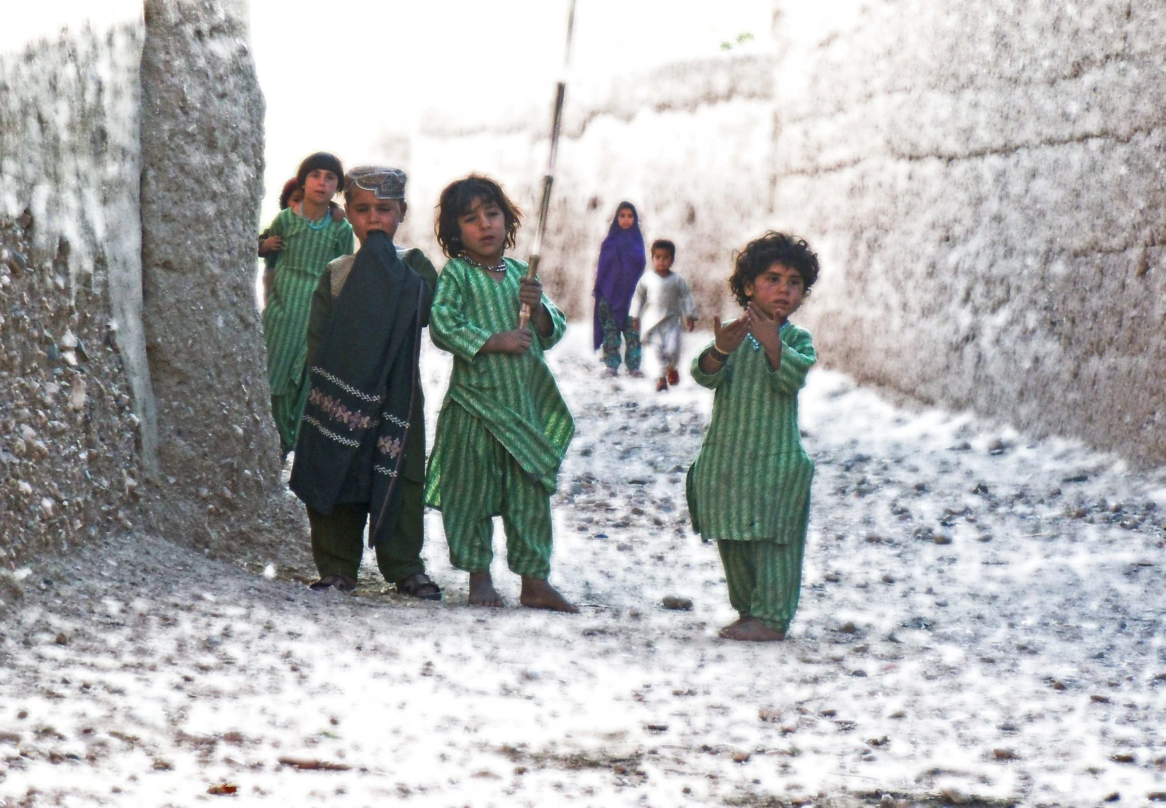 children are walking along a street with snow on the ground