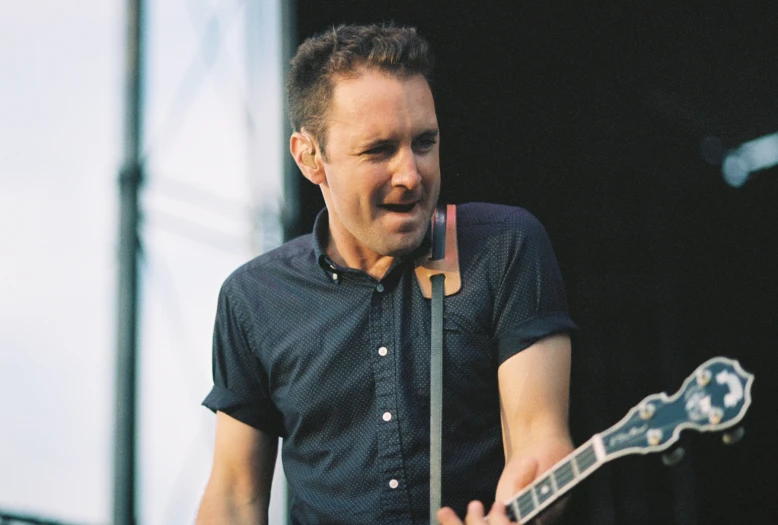 a man holding a guitar standing in front of a stage