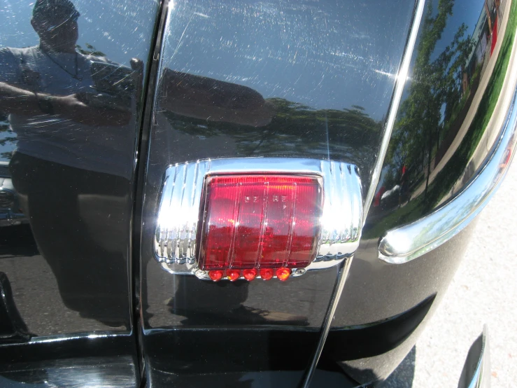 the rear end of a black car with a red light on it