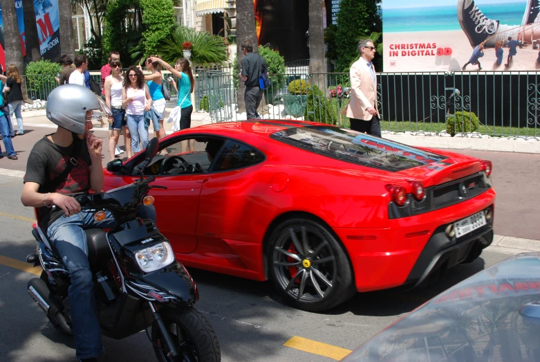 two people standing near a parked red car