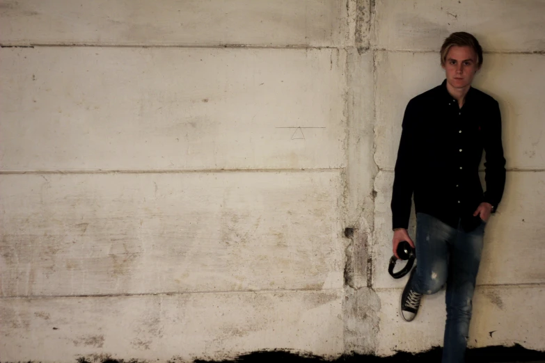 a person leaning against a wall with their skateboard