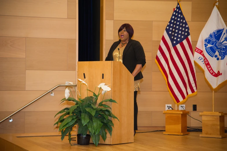 a woman stands behind a podium while speaking