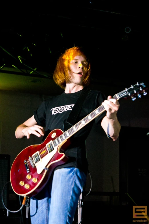 a man with bright red hair playing a guitar