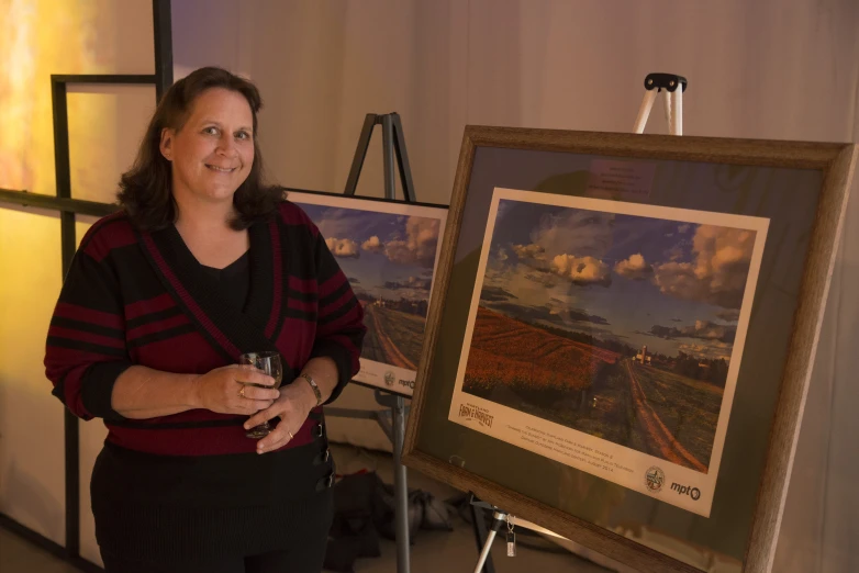 a lady standing next to an art display and wine glass