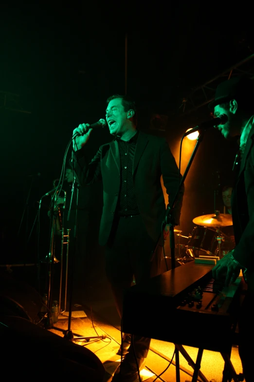 two men in suits singing into microphones at night