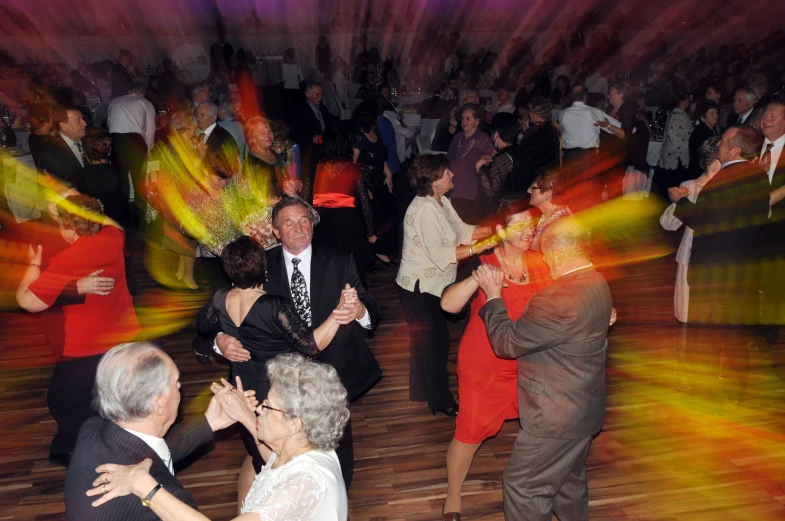 people dancing on a wooden floor as a man and woman hug and clap