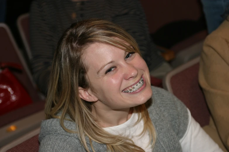 a smiling girl sitting in front of some chairs