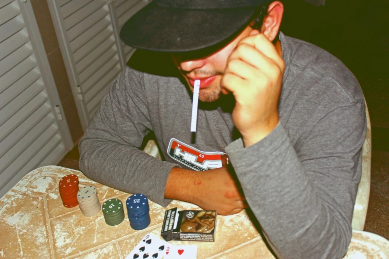 man holding cigarette and chewing on a card set with playing cards