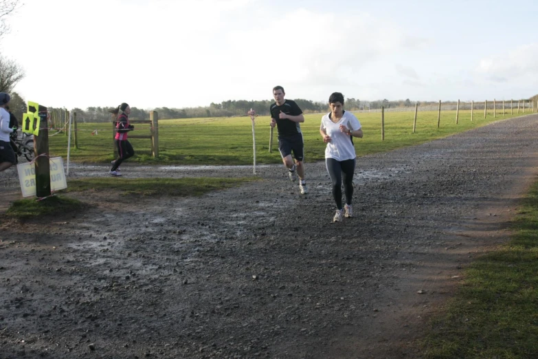 a group of people running on dirt road next to trees