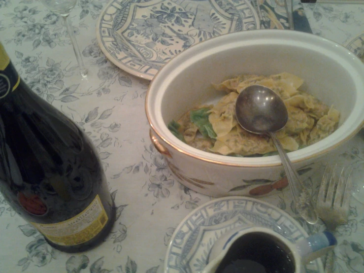 there is a pasta dish in a bowl on the table next to the bottle