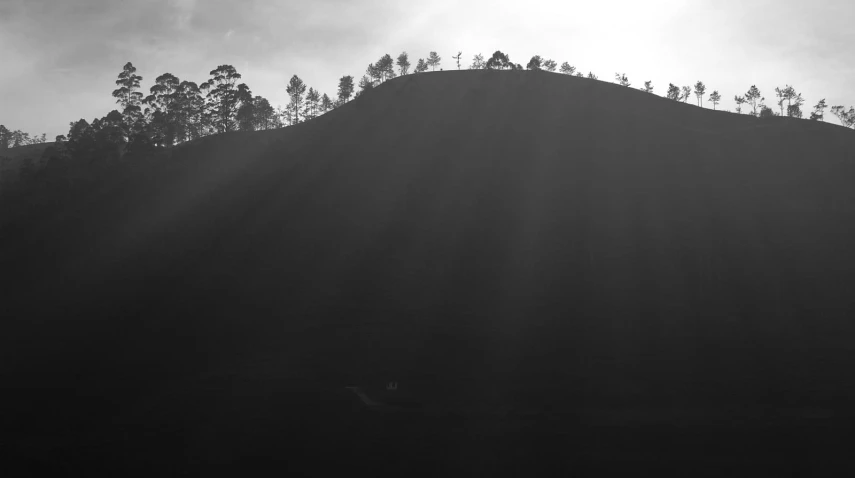 a silhouette of the hill against a dark, cloudy sky