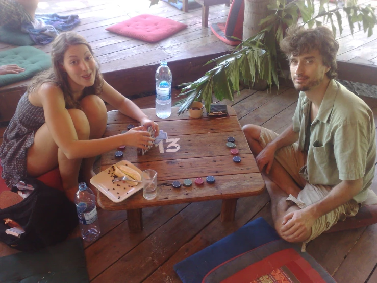 a young man and woman sitting at a table playing a game