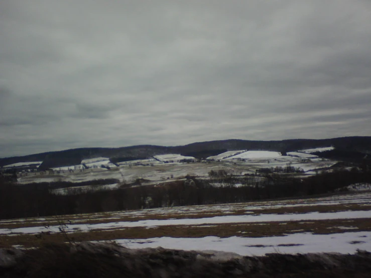 a farm on a cold snowy day with mountains and fields in the background