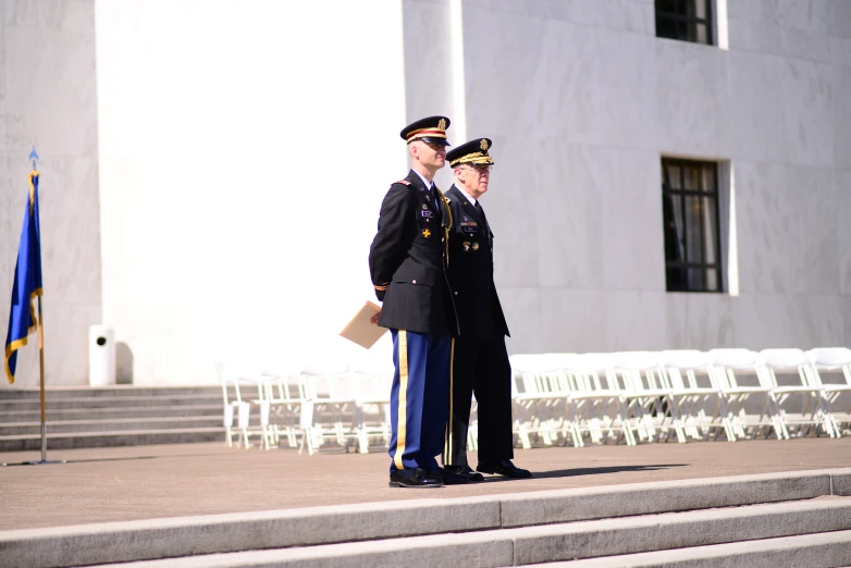 two men in uniforms standing at the stairs of an outside auditorium