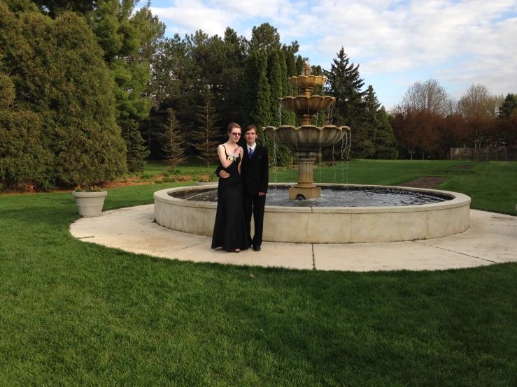 two people are standing by a fountain in a formal setting