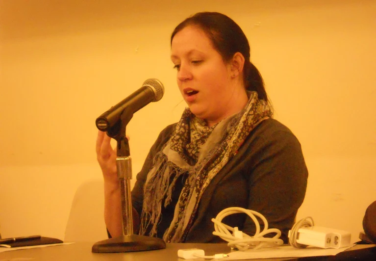 a woman is sitting in front of a microphone and holding her headphones