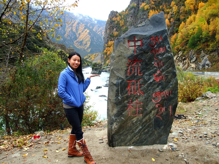 a woman standing in front of a large rock