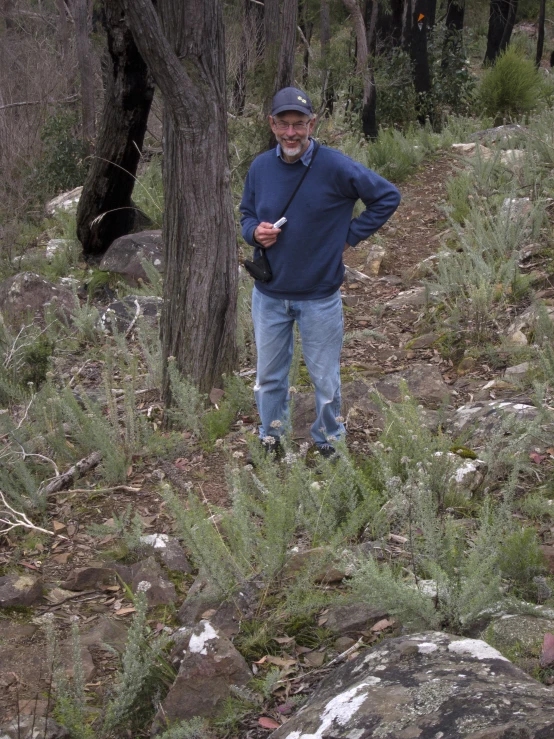 a man in blue jacket standing by a tree