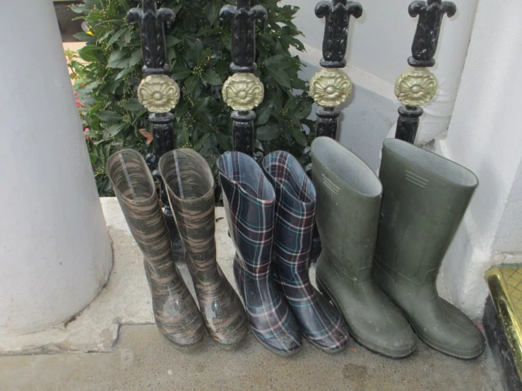 several rain boots and water shoes sitting in front of two pillars