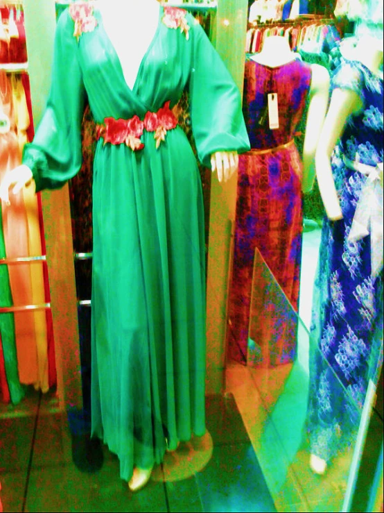 a woman's dress with a long skirt and flowers sits on a mannequin