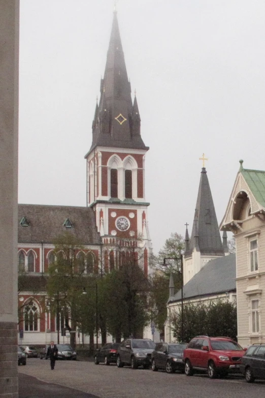 a church steeple towering over many parked cars