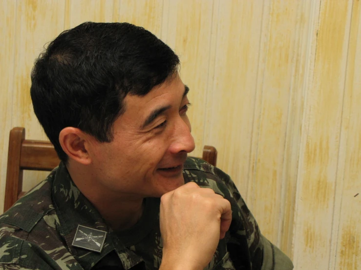 a man in camouflage shirt smiling and wearing his tie