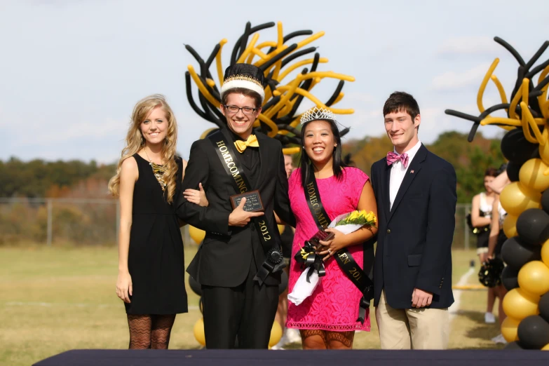 three young people smile for the camera as they pose with their man and woman in front of an elaborate flower display