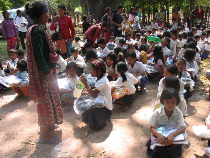 several school children are sitting together while a person stands behind them