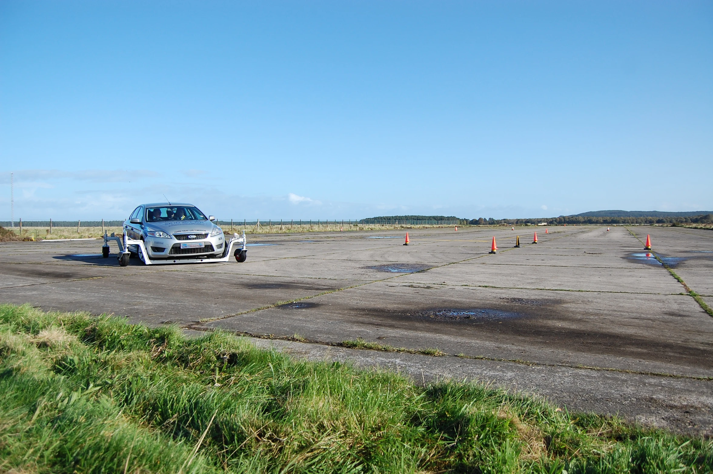 a silver car in an empty lot near a field