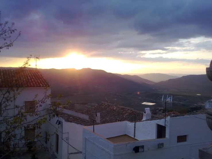 the sun sets over the countryside with the mountains in the background