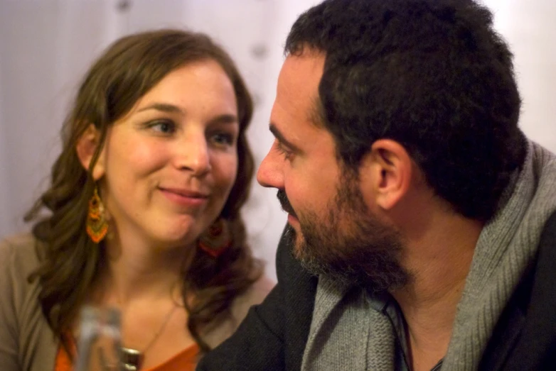 a man and a woman sit with drinks in front of each other