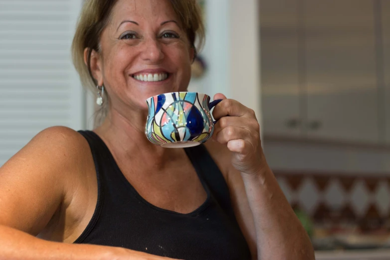 smiling woman drinking a cup of coffee while smiling at the camera