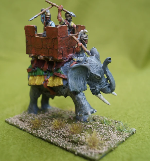 the toy figurine shows two men riding on an elephant