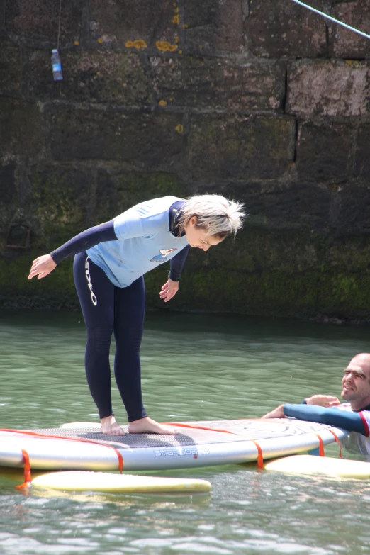 a man standing on top of a paddle board next to another person