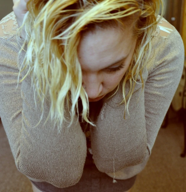 a woman has blonde hair with her hand to her head