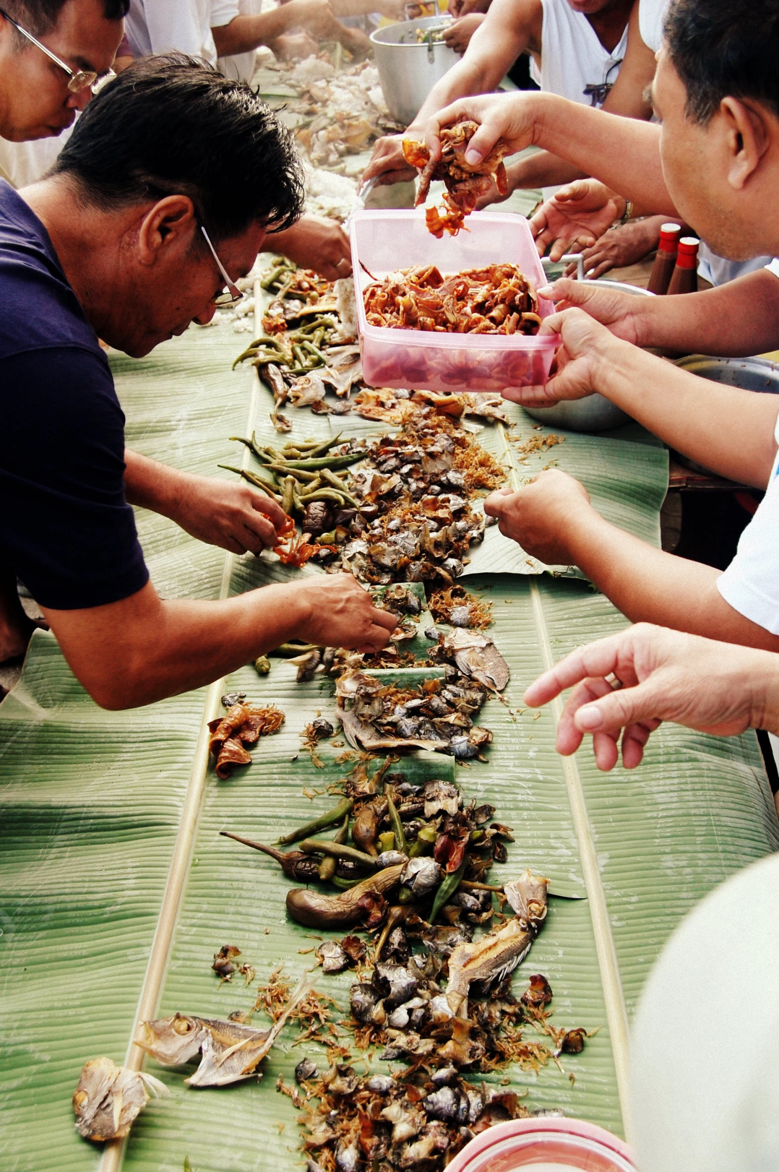 people are serving themselves food on the long table